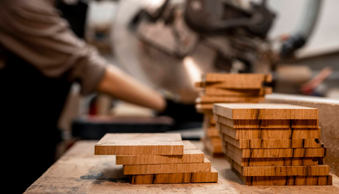 Woodworking shop with cut wood planks and a saw in the background